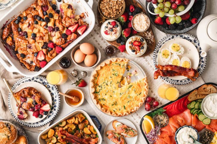 A brunch menu featuring a quiche, berry casserole, smoked salmon and other breakfast foods on a white background.