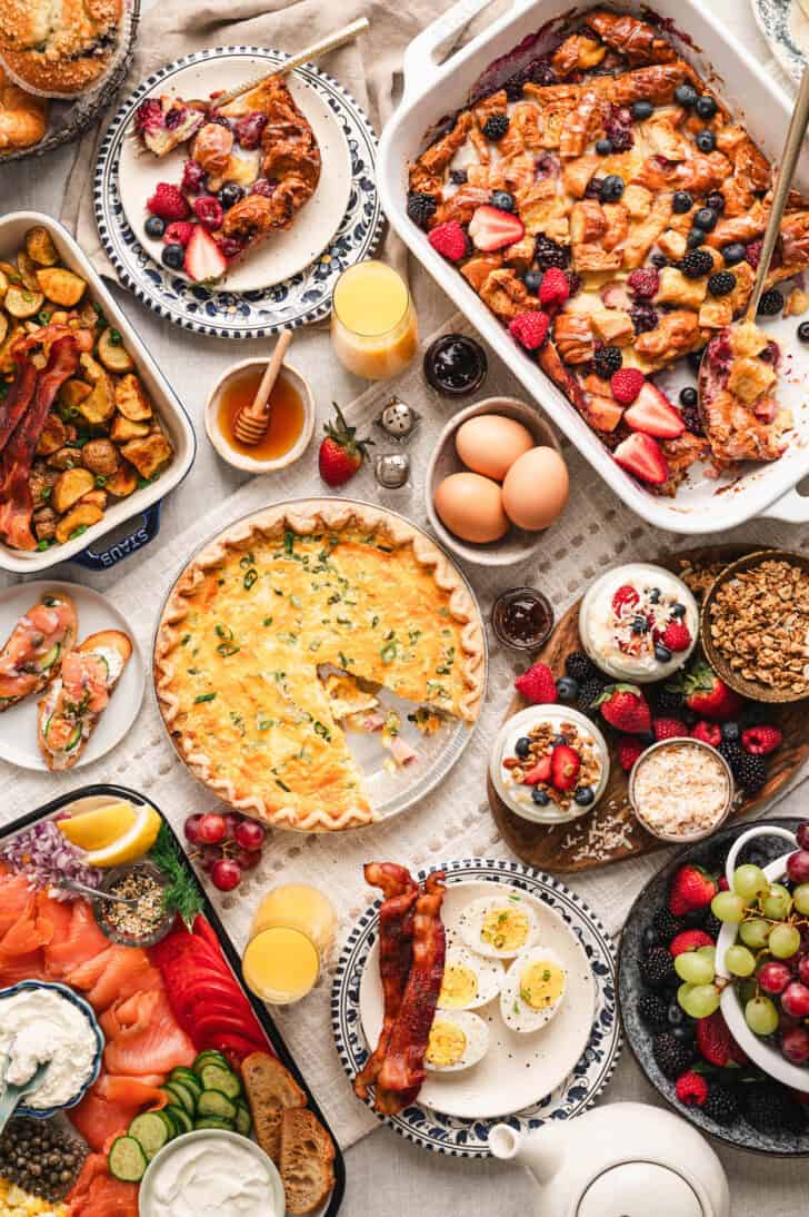 A brunch menu featuring a quiche, berry casserole, smoked salmon and other breakfast foods on a white background.