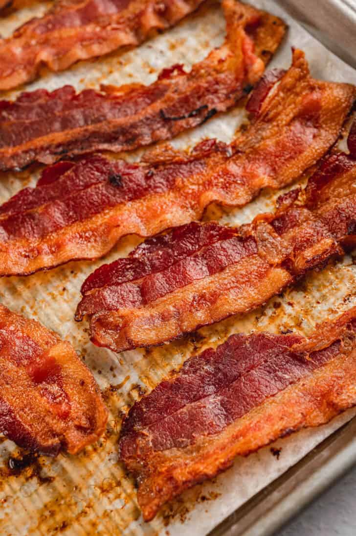 Bacon in oven on a parchment paper lined baking pan.