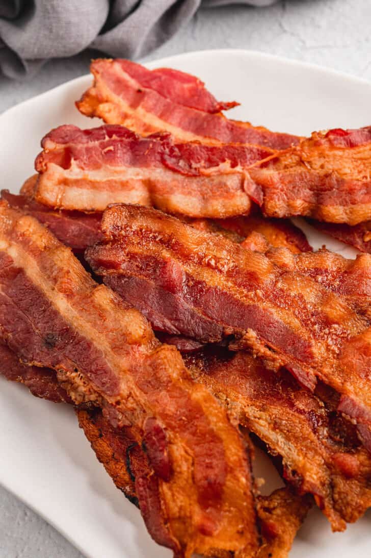 A plate of bacon slices cooked in the oven until crispy.