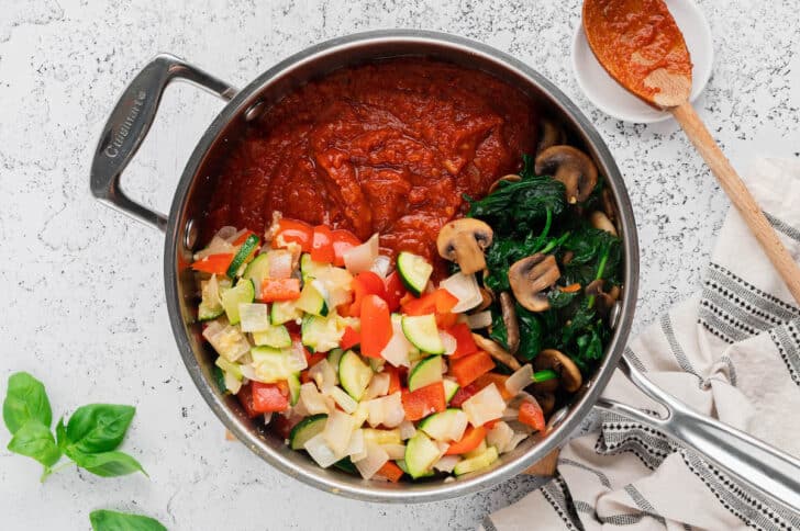 Sauteed vegetables, spinach, mushrooms and marinara sauce in a skillet.