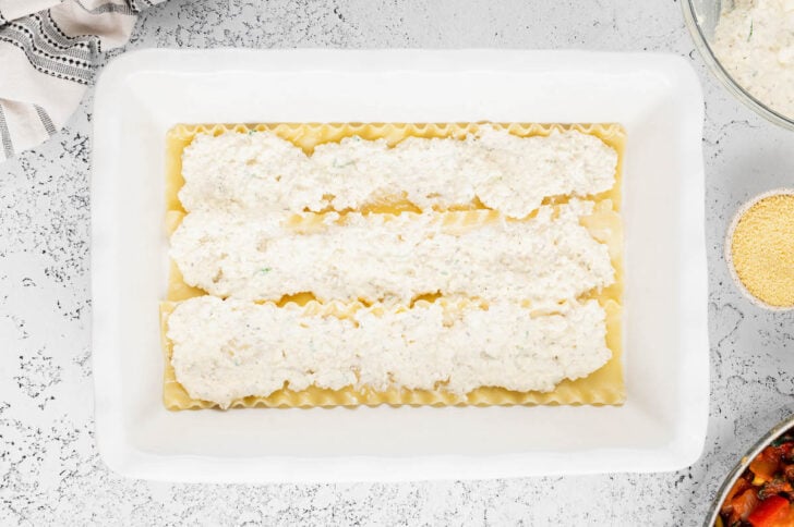 A white lasagna dish layered with lasagna noodles and a cheese mixture.