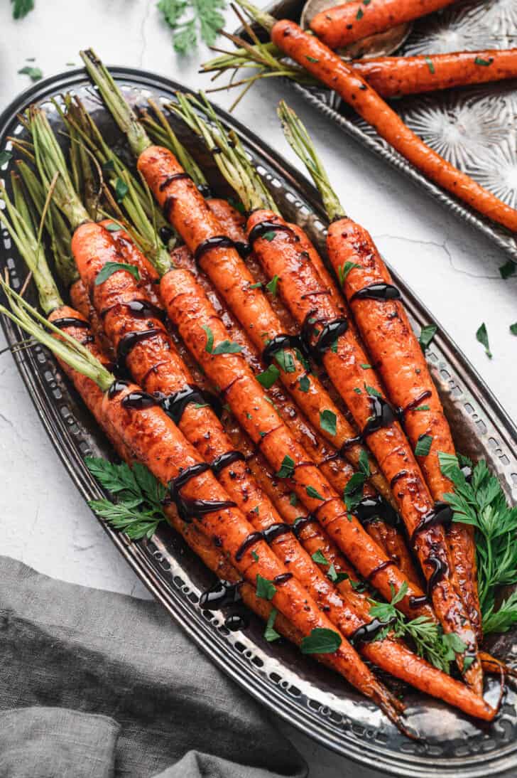 A metal serving dish filled with balsamic carrots.