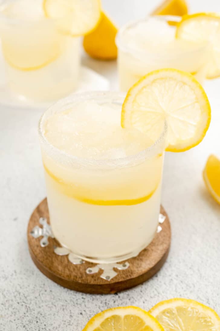 A small glass filled with an icy mostly clear liquid, garnished with lemon slices.