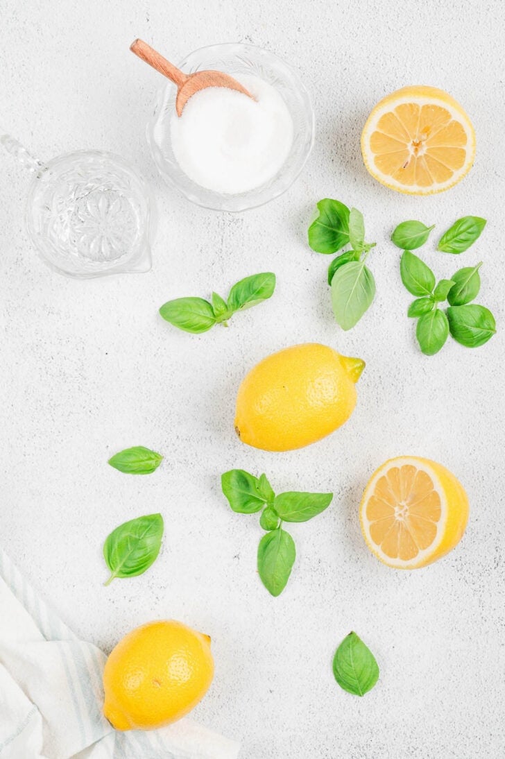 Ingredients on a white background, including lemons, sugar and basil.