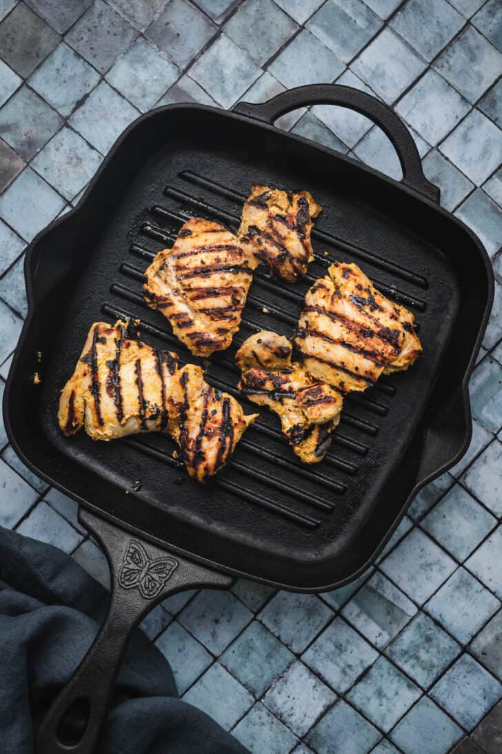 Grilled poultry thighs on a square grill pan.