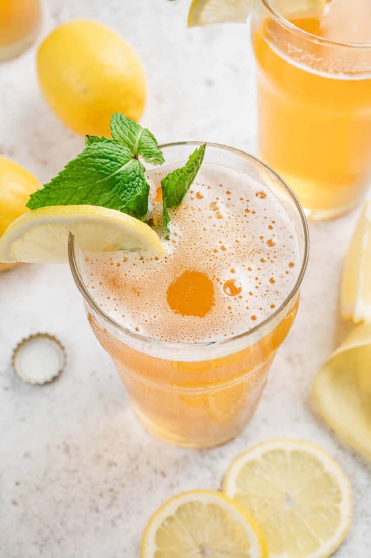 A pint glassed filled with lemon beer, garnished with mint and lemon slices.