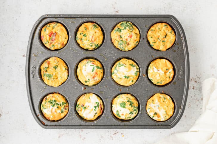 A muffin pan with the holes filled with egg muffins.