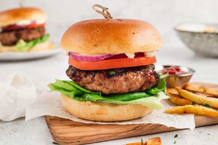 A turkey burger on a brioche bun with lettuce, tomato, onion and mayonnaise.