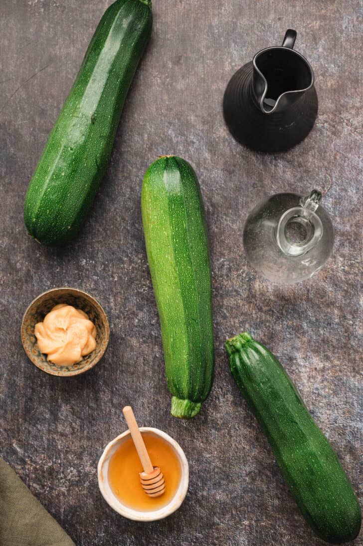 Ingredients on a textured surface, including summer squash, miso, honey, vinegar and soy sauce.