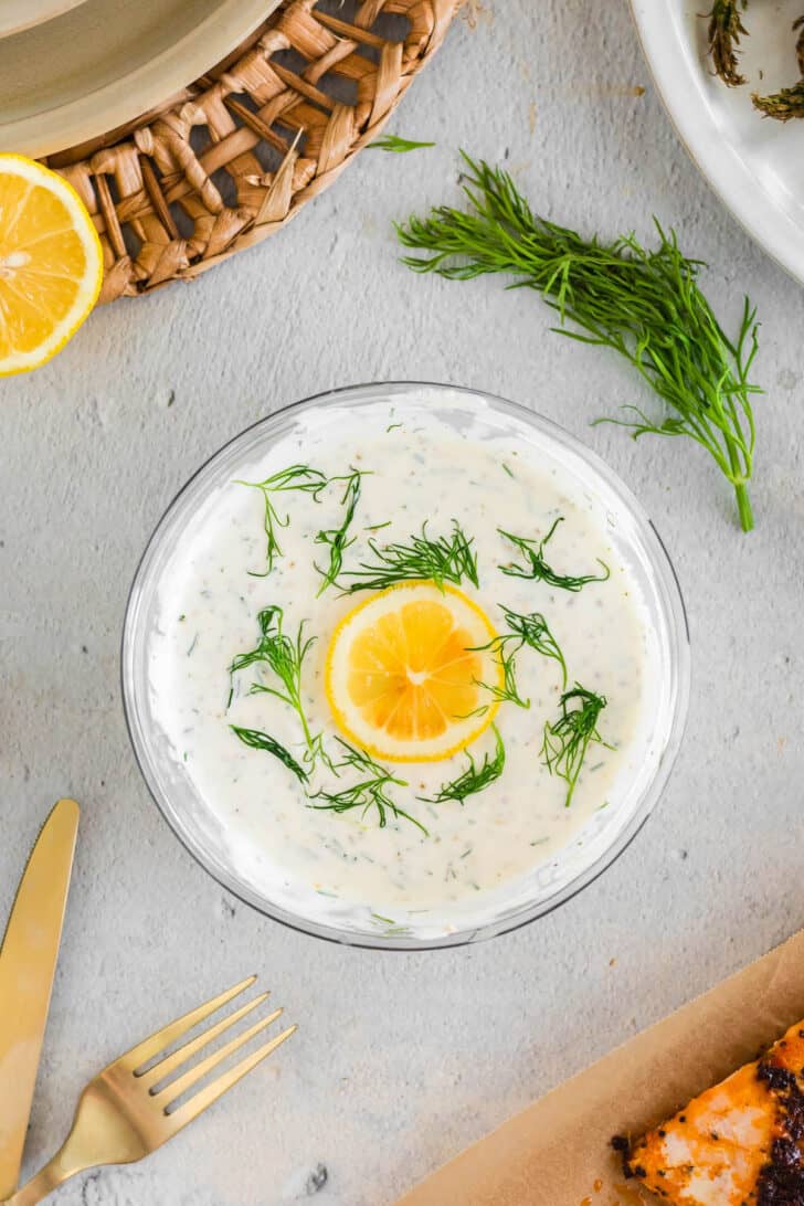 A glass bowl filled with a creamy herb sauce.