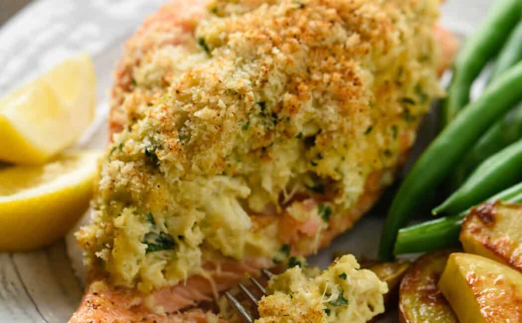 Closeup on piece of crab stuffed salmon topped with breadcrumbs, with fork taking a piece.