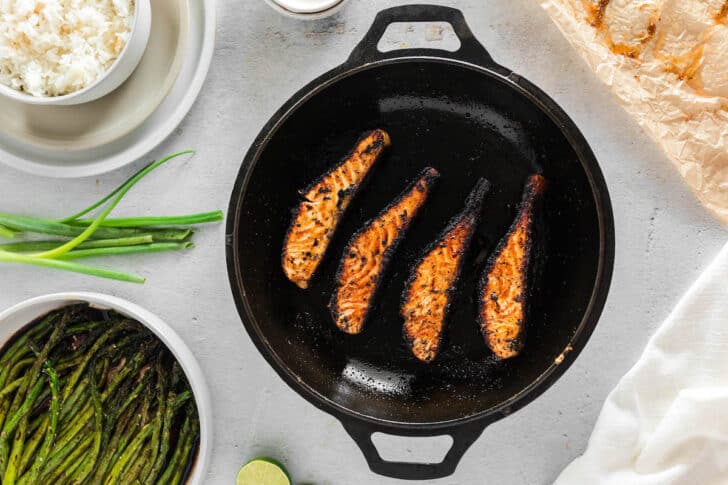 A blackened salmon recipe in the process of being seared in a cast iron pan.