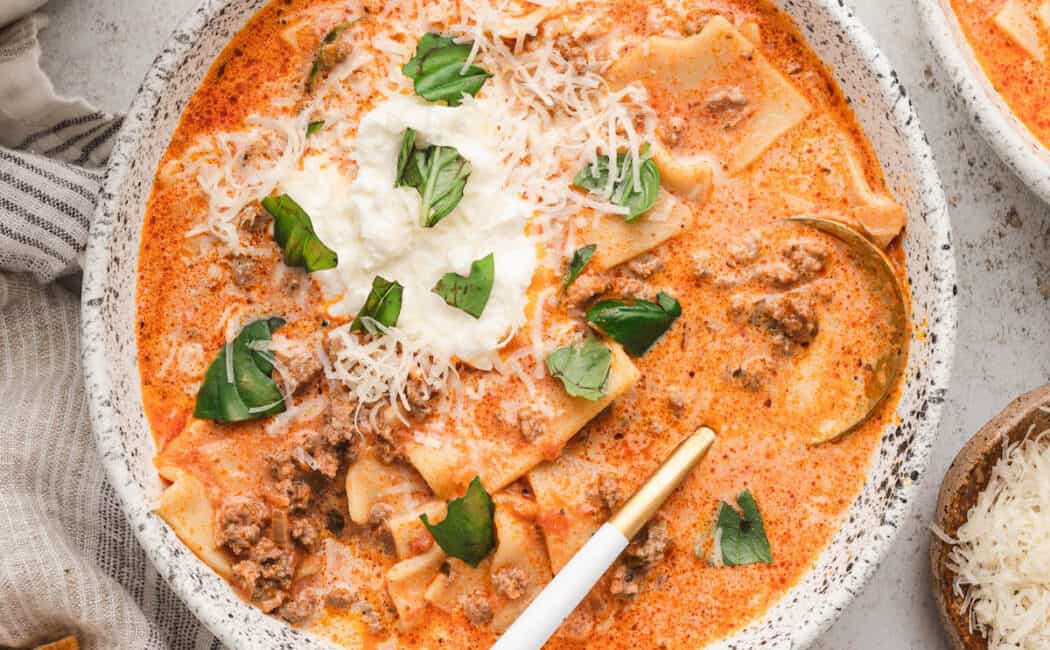 Creamy Lasagna Soup in a rustic bowl, topped with ricotta, Parmesan cheese and fresh basil.