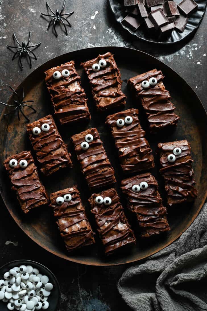 Halloween brownies that look like mummies on a rustic round tray.