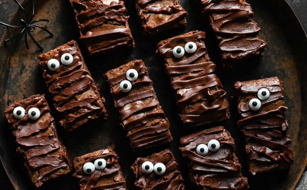 Halloween brownies that look like mummies on a rustic round tray.