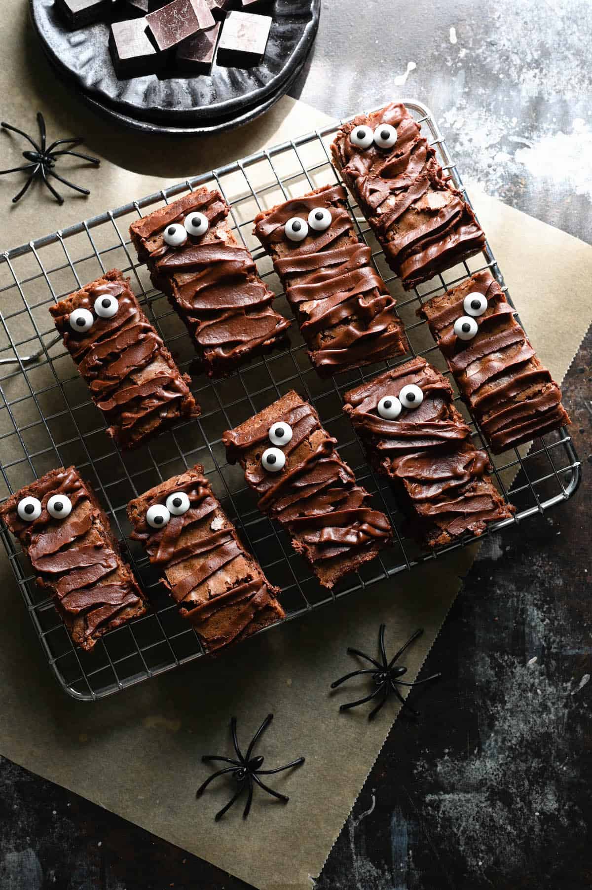 Halloween chocolate brownies that resemble mummies on a metal cooling rack.