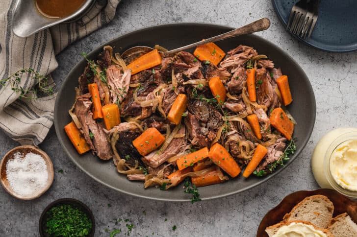 A platter of pork roast slow cooker with onions, thyme and carrots.