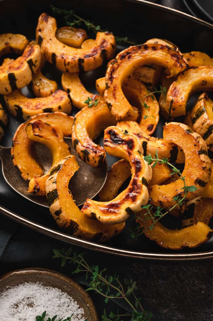 A delicata squash recipe being served on a black serving platter.
