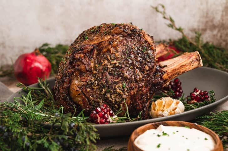 A standing rib roast covered in prime rib rub in a festive holiday dinner table scene.