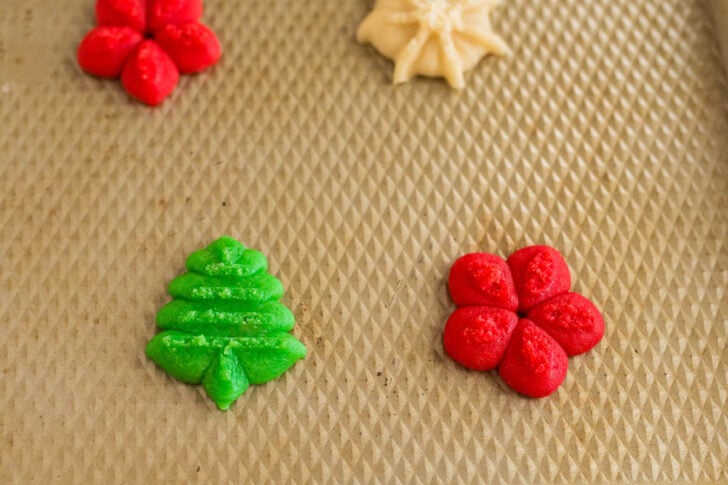 Christmas spritz cookies on a textured gold pan.