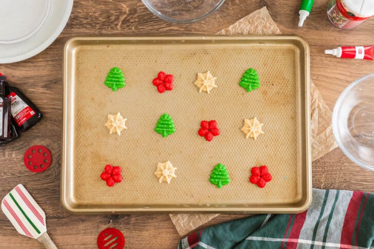 Christmas spritz cookies on a textured gold pan.