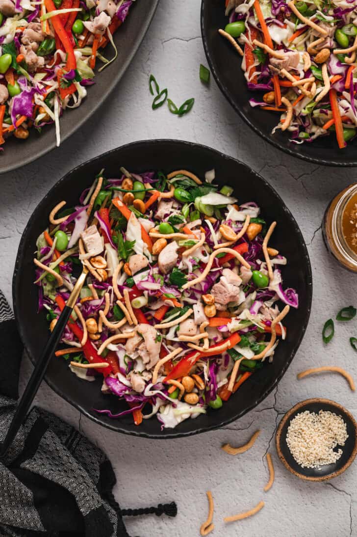A dark round bowl filled with an Asian chicken salad recipe.