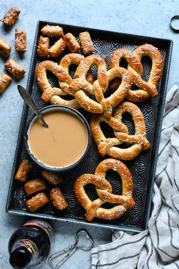 A bowl of beer cheese dip surrounded by soft pretzels.