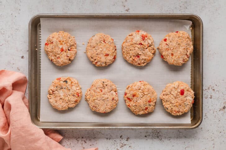 Eight easy salmon patties on a parchment paper-lined baking pan.