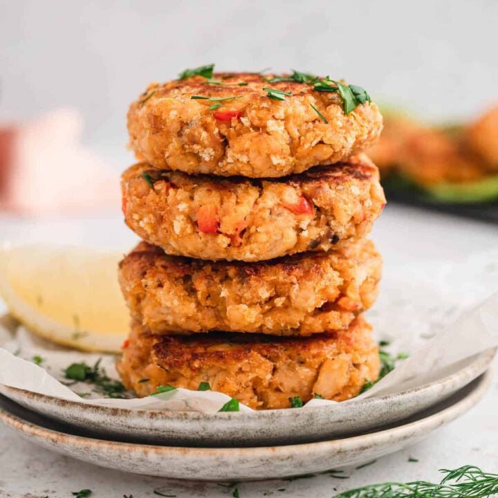 A stack of four canned salmon patties on a small white plate.