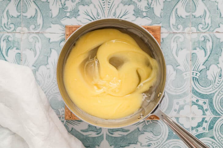 A saucepan with a creamy yellow mixture swirled over a thick clear mixture.