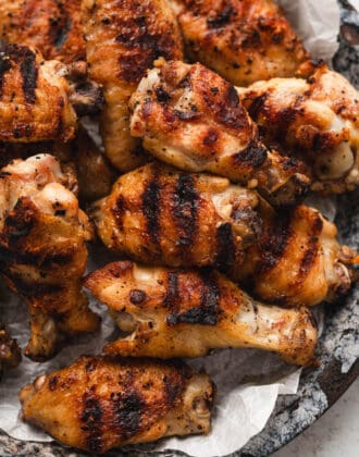 A pile of grilled chicken wings on a round platter.