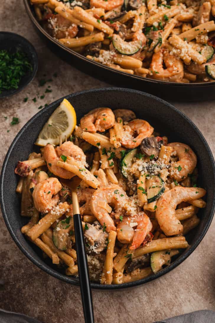 A dark bowl filled with easy Cajun shrimp pasta, with a fork digging in.