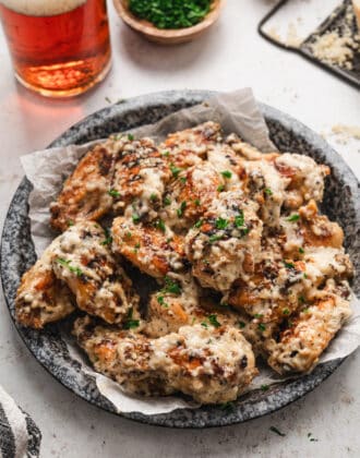 A round textured pie plate topped with chicken wings coated in garlic parmesan wing sauce.