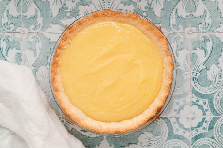 A baked pie crust filled with a creamy yellow mixture.