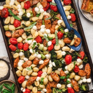 A sheet pan gnocchi dinner with a spoon digging into it.