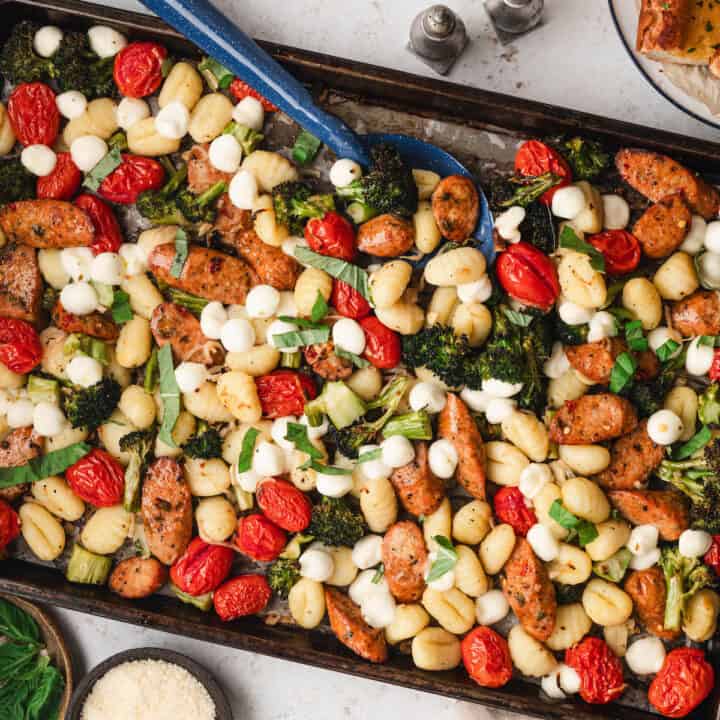 A sheet pan gnocchi dinner with a spoon digging into it.