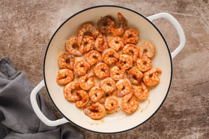A white Dutch oven filled with cooked shrimp.