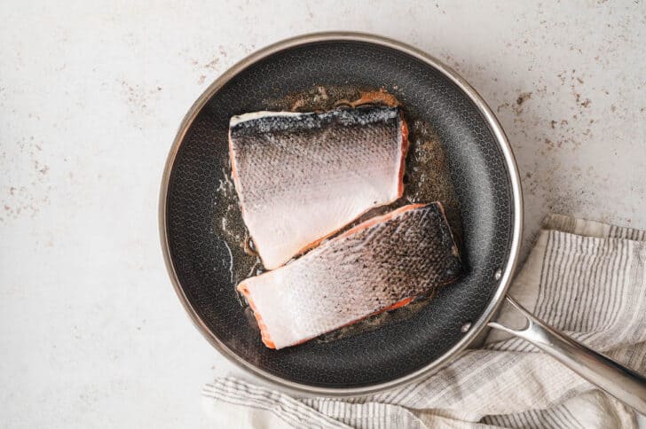 Two salmon fillets flesh side down in a nonstick skillet.