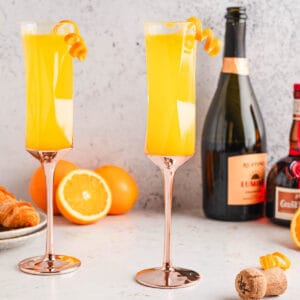 Two glasses of the best mimosa recipe, garnished with orange peel curls.