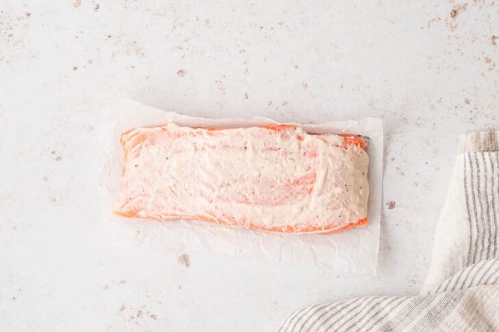 A raw salmon fillet brushed with a creamy sauce.