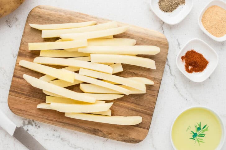 Sliced potatoes on a wooden cutting board.