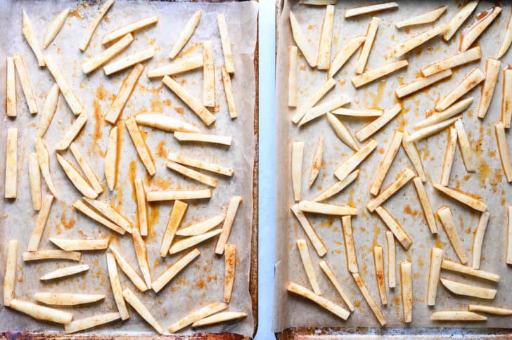 Sliced potatoes on parchment-lined baking pans.