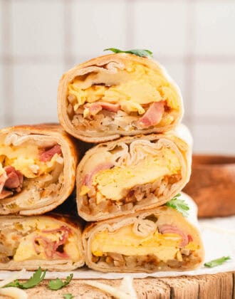 A stack of the best breakfast burritos in front of a light tile background.