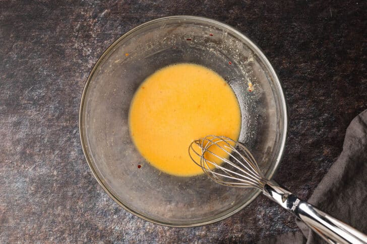 A glass bowl filled with yellow salad dressing.