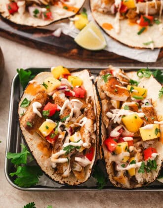 The best fish tacos topped with tropical fruit salsa and drizzled with creamy sauce.