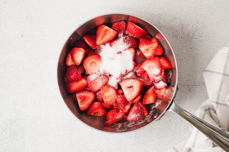 A saucepan filled with cut strawberries and sugar.