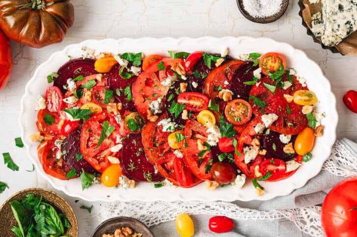 An heirloom tomato salad on a white serving platter.