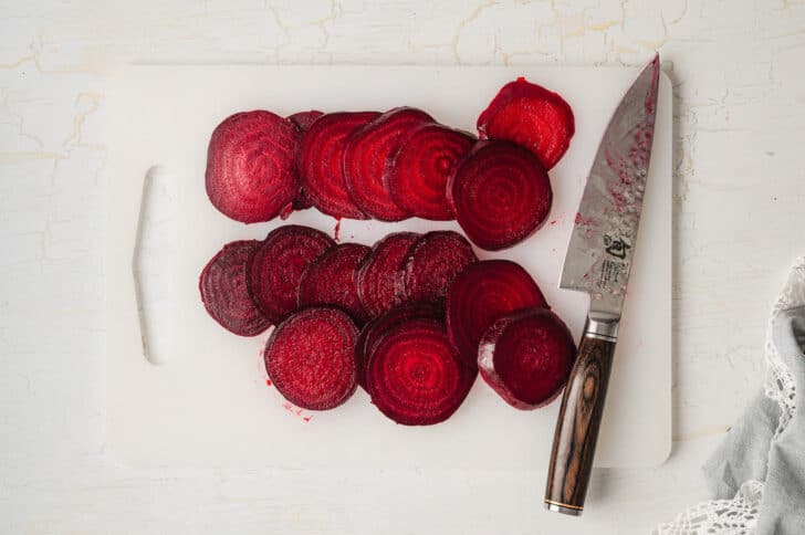 Sliced red root vegetables on a white cutting board.