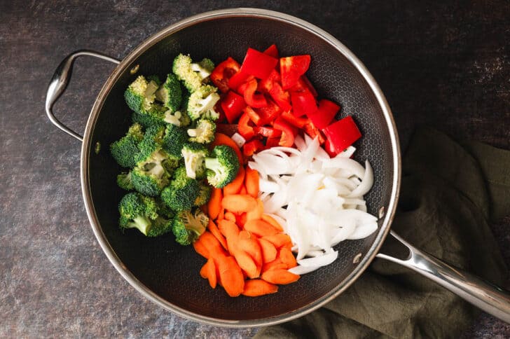 A black skillet filled with broccoli, red pepper, onion and carrot.